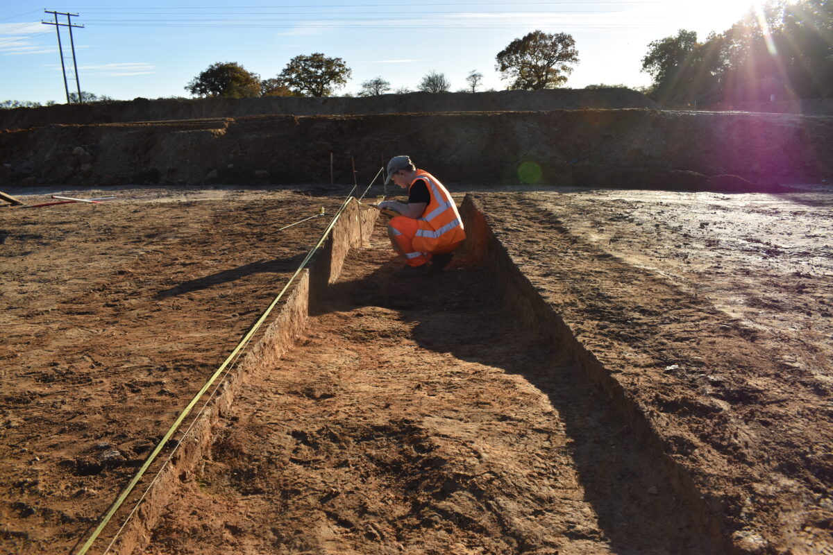 Archaeologist recording section of archaeological feature in the August sunshine