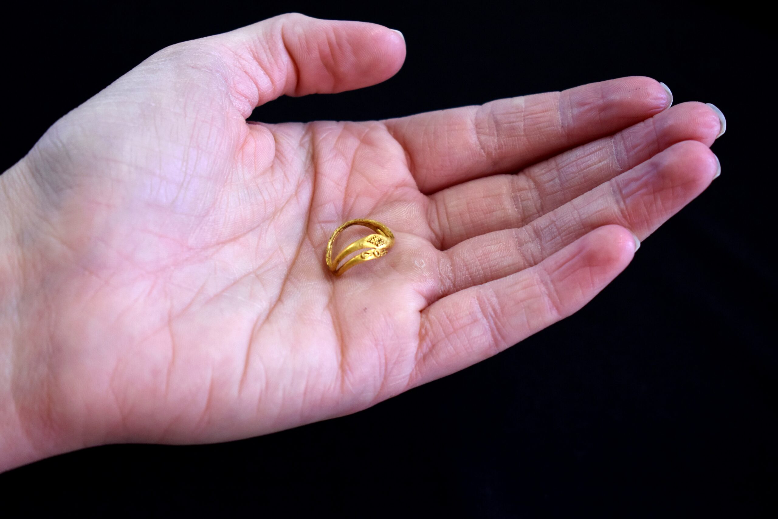 Image of a gold ring in the centre of a hand to show scale