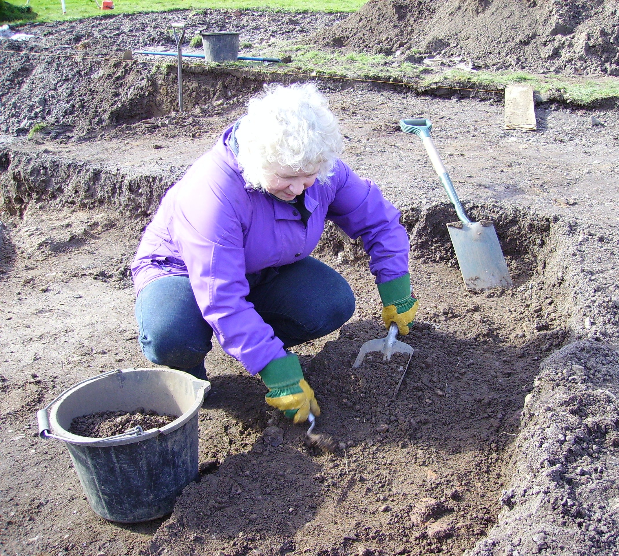 Barbara Butler dressed in purple raincoat digging on the starting gates at the Sergeants Mess